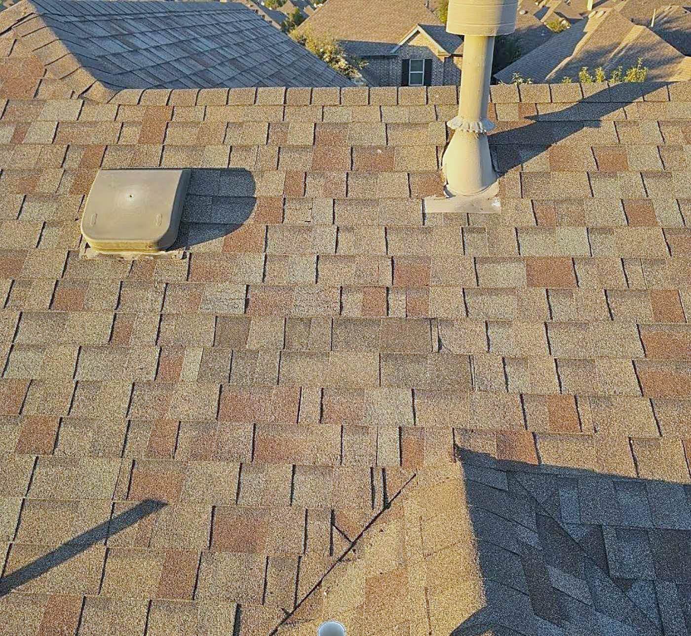 A field of warm brown architectural shingles around a pipe boot